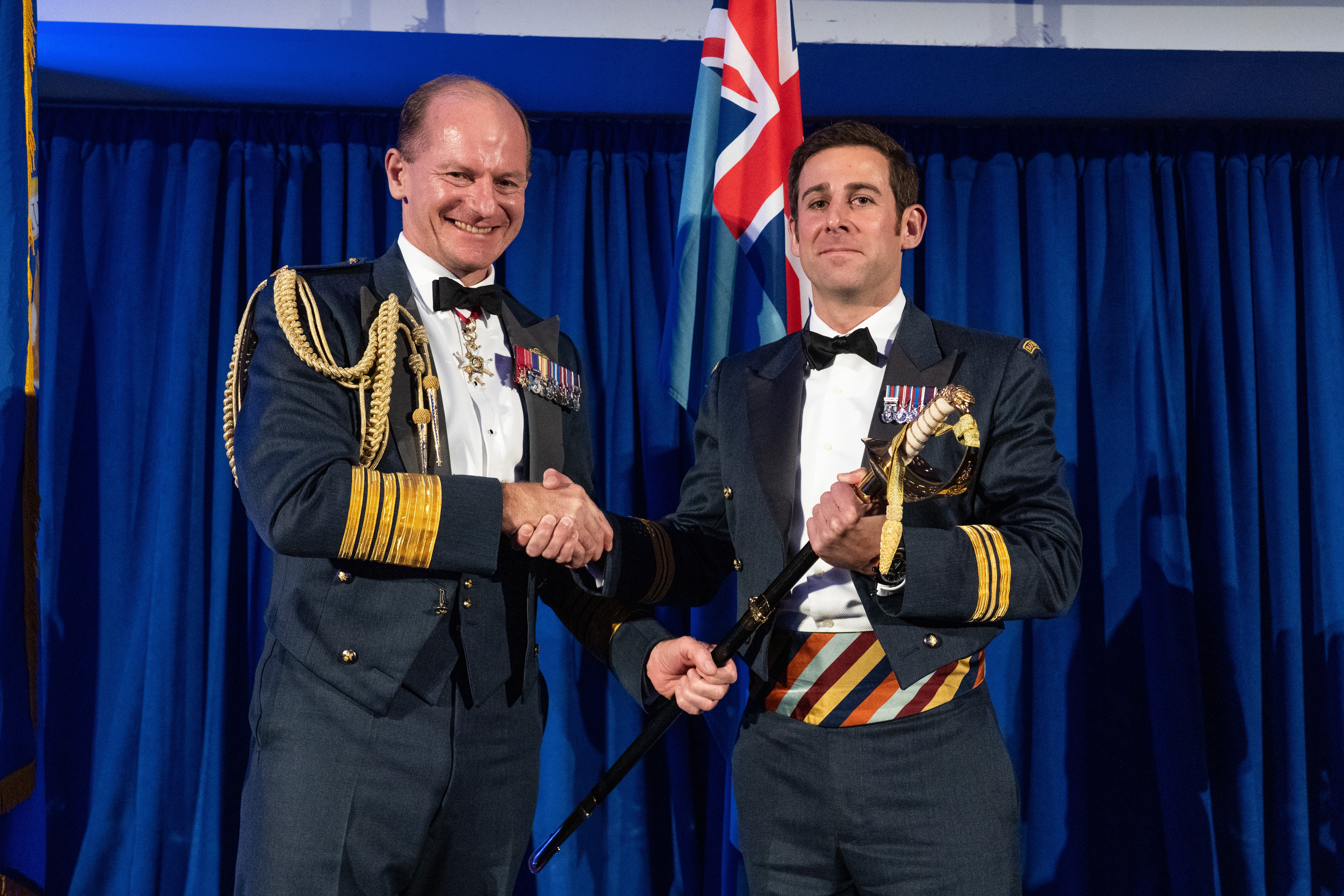 Image shows Air Chief Marshal Sir Mike Wigston shaking hands with Christopher as he awards him the sword.